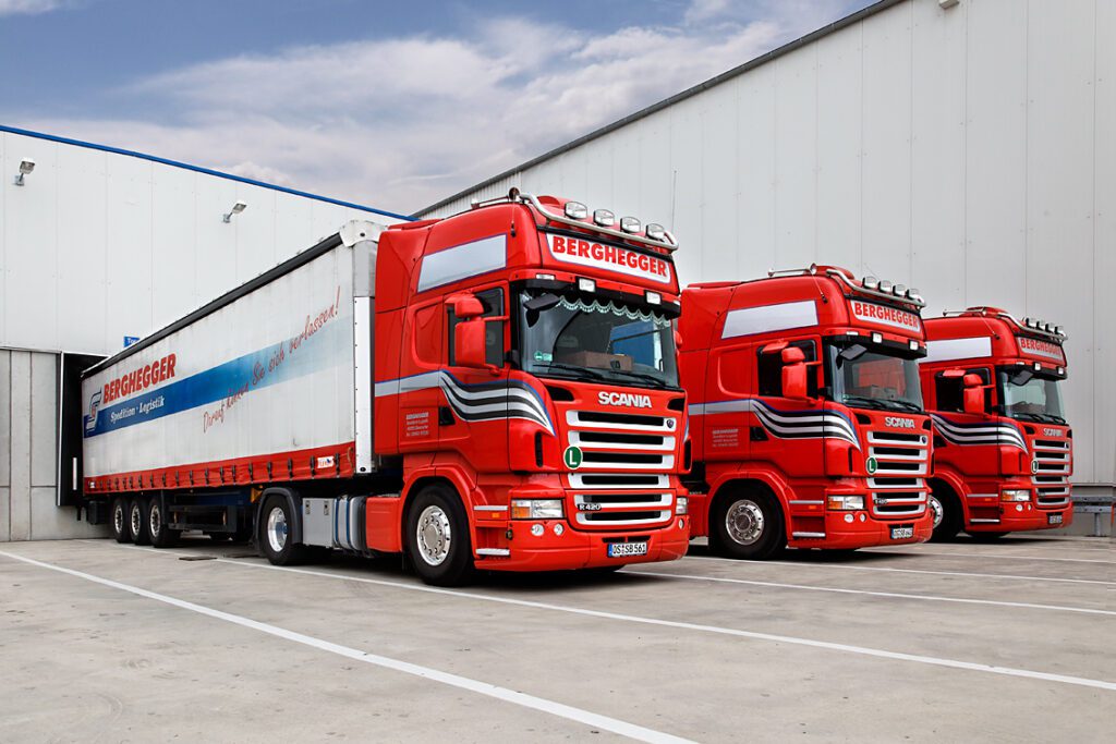 Drei LKW der Berghegger Internationale Spedition GMBH, ein Unternehmen der Maintrans Gruppe, stehen an der Laderampe des Logistik-Lagers und werden beladen.