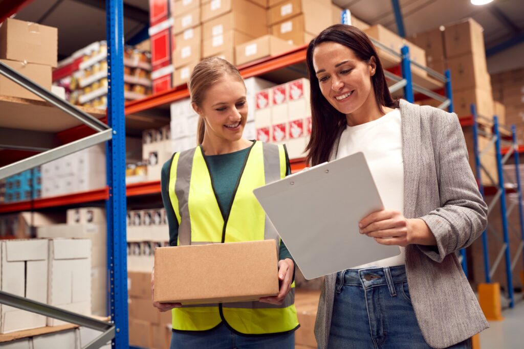 Zwei Lagermitarbeiterinnen gehen gemeinsam eine Checkliste im Logistik-Lager durch.